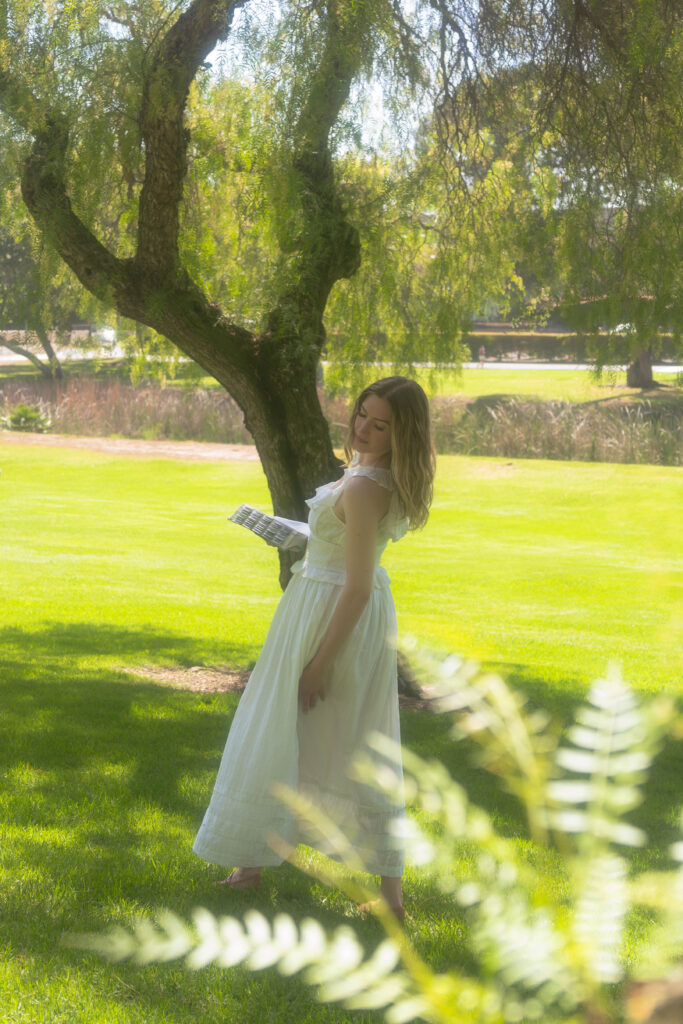 A woman standing by a tree with a bible in her hand, reflecting on her journey of healing and faith.