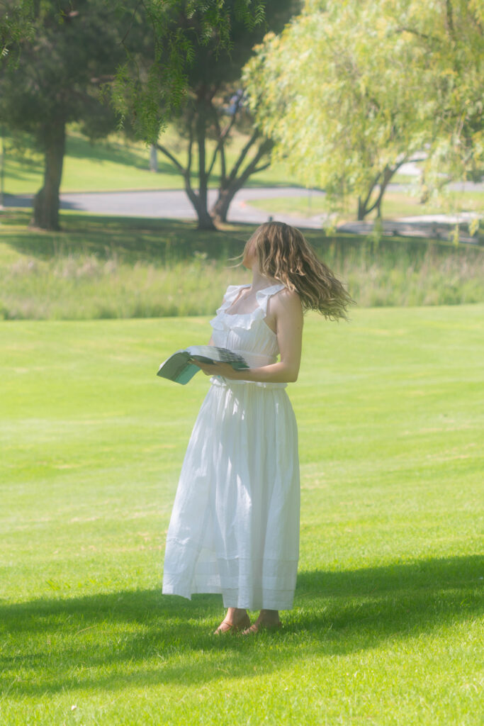 Woman standing in a sunlit field, holding a Bible and looking over her shoulder, reflecting on faith, healing, and self-trust.