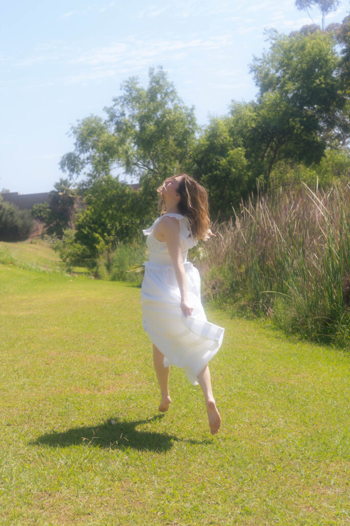 woman running in field chasing after rainbows