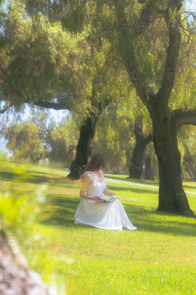 Woman sitting in a grass patch reading her Bible, reflecting on healing from a toxic childhood friendship and learning boundaries in faith