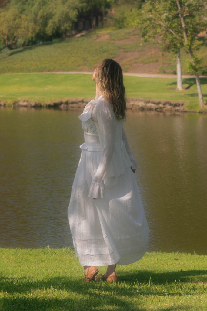 Woman standing by a lake contemplating healing as more than naming trauma